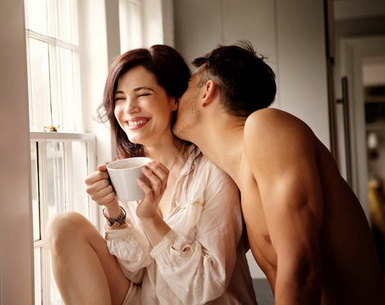 Man kissing, teasing woman over coffee